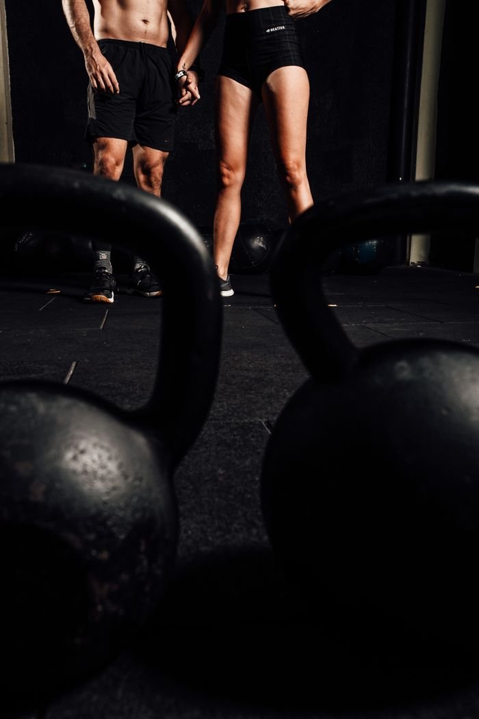 why-choose-us Man and woman in gym with kettlebells, embracing a healthy lifestyle.