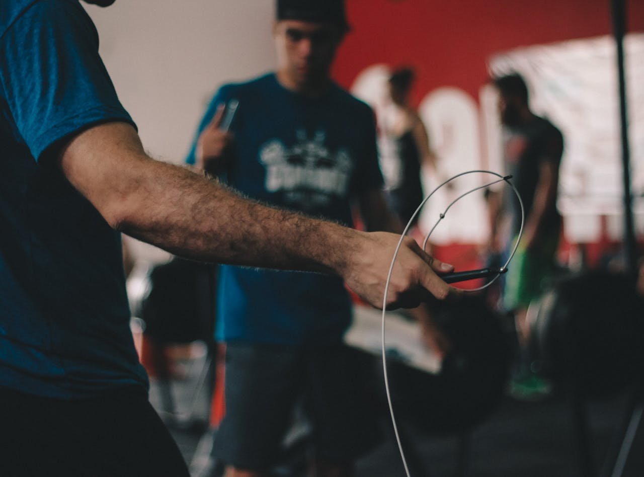 gallery-4 Adult man performing jump rope exercise indoors at a gym during the day.